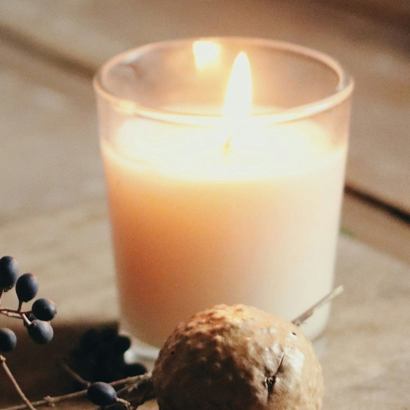 White Tea Votive — The flame of a glass votive candle glowing through cream wax